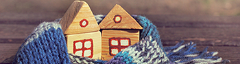 Duas casa de madeira com telhado e 1 janela cada, embrulhadas num cachecol de lã