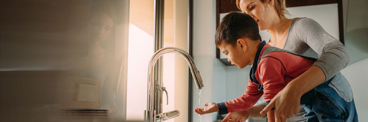 Mãe a lavar as mãos ao filho numa torneira